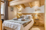 Experience the charm of this cozy bedroom featuring a rustic wooden headboard and ceiling beams, creating a warm and inviting atmosphere.