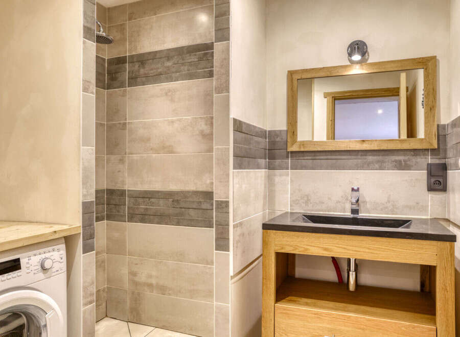 This stunning bathroom features a modern design with a sleek black countertop and a wooden vanity.
