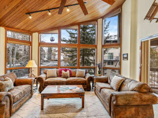 Experience luxury living in this stunning property, featuring a cozy living room with a unique wooden ceiling and expansive windows that offer breathtaking views of the surrounding landscape.