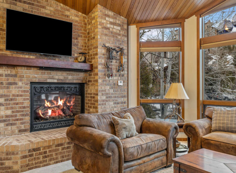 Experience the warmth of this inviting living space, featuring a cozy fireplace and exposed brick accents.
