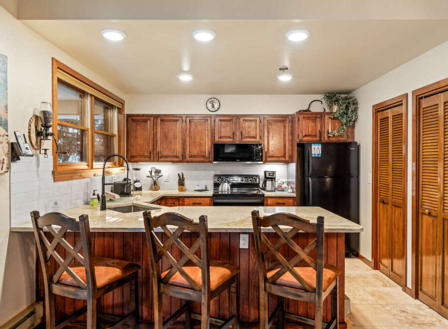 Step into this inviting kitchen, featuring warm wooden cabinetry and a stylish breakfast bar perfect for casual dining.