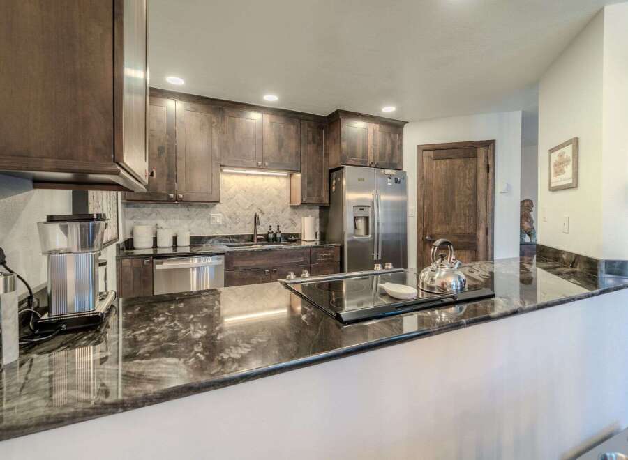 This stunning kitchen boasts dark wood cabinetry, stainless steel appliances, and a sleek cooktop.