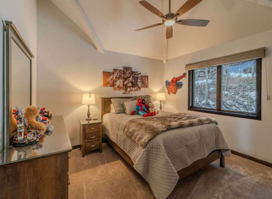 This cozy bedroom features a comfortable bed with a stylish faux fur throw and a charming Spiderman wall decor.