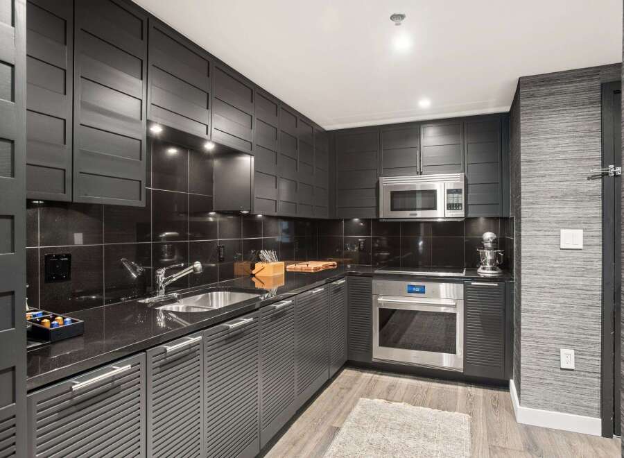 This modern kitchen boasts sleek, dark cabinetry and countertops, creating a sophisticated and stylish space.