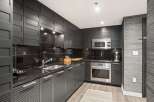 This modern kitchen boasts sleek, dark cabinetry and countertops, creating a sophisticated and stylish space.