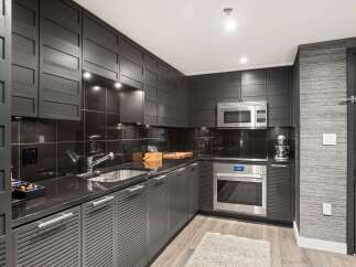 This modern kitchen boasts sleek, dark cabinetry and countertops, creating a sophisticated and stylish space.
