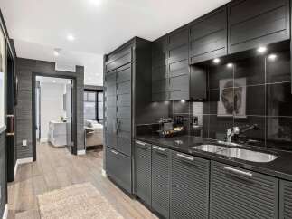 This stunning kitchen boasts sleek, modern design with dark cabinetry and countertops.