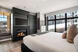 Experience luxury living in this stunning bedroom featuring a cozy fireplace and a large flat-screen TV.