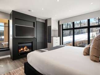 Experience luxury living in this stunning bedroom featuring a cozy fireplace and a large flat-screen TV.