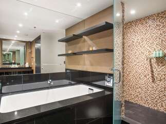 Indulge in luxury within this stunning bathroom, featuring a sleek black granite countertop and a pristine white bathtub.