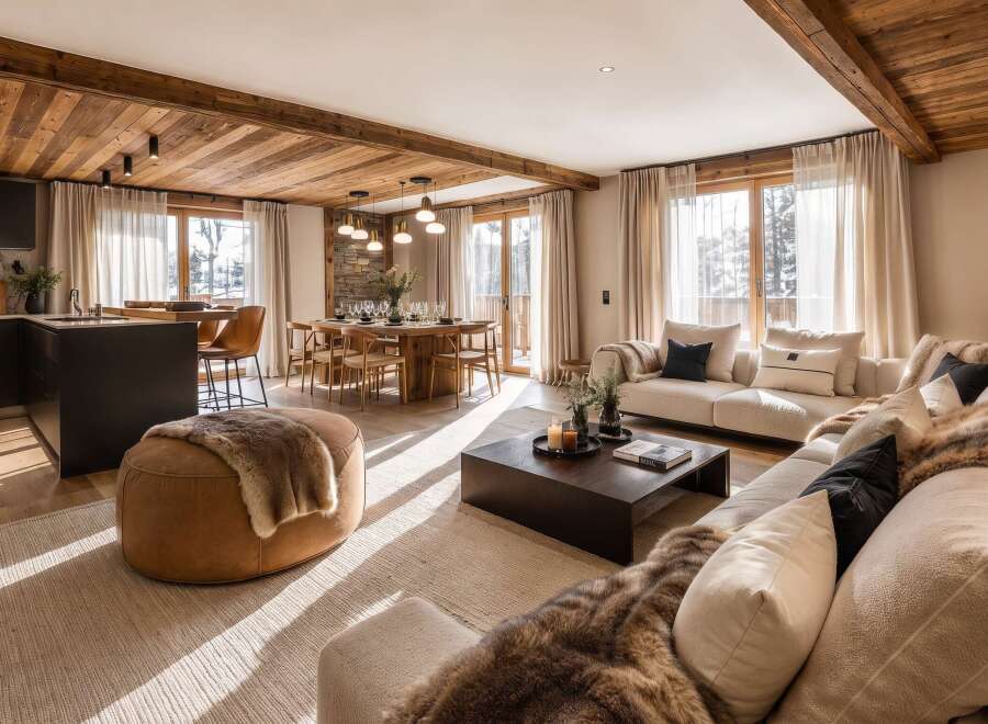 Experience luxury mountain living in this stunning open-concept space, featuring a modern kitchen with dark cabinetry and a sleek island, flowing seamlessly into a warm dining area and a cozy living room.