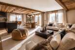 Experience luxury mountain living in this stunning open-concept space, featuring a modern kitchen with dark cabinetry and a sleek island, flowing seamlessly into a warm dining area and a cozy living room.