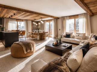 Experience luxury mountain living in this stunning open-concept space, featuring a modern kitchen with dark cabinetry and a sleek island, flowing seamlessly into a warm dining area and a cozy living room.