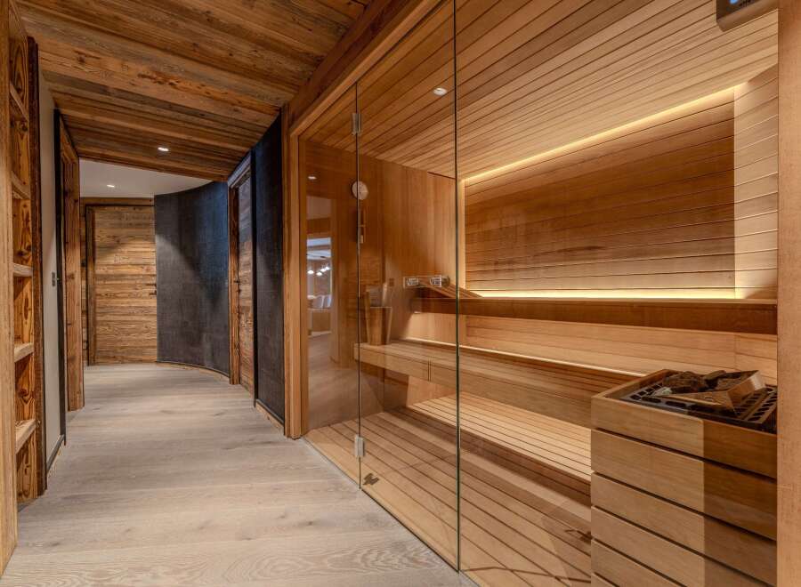 Experience ultimate relaxation in this luxurious spa area, featuring a modern glass-enclosed sauna with warm wood paneling and ambient lighting.