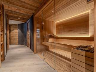 Experience ultimate relaxation in this luxurious spa area, featuring a modern glass-enclosed sauna with warm wood paneling and ambient lighting.