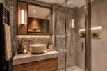 Experience luxury in this modern bathroom featuring a sleek concrete countertop with a vessel sink and a wooden vanity.