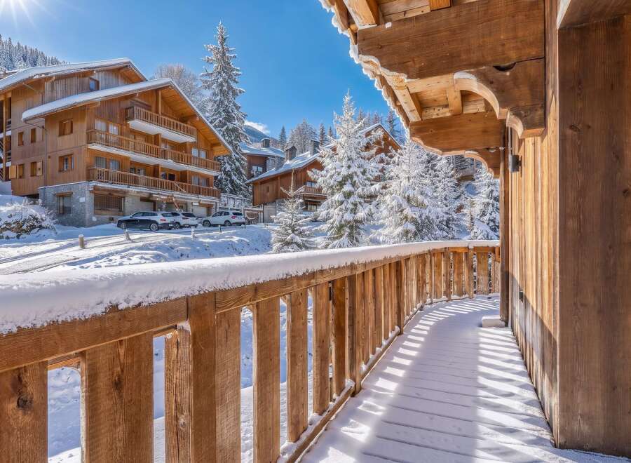 Experience the charm of a winter wonderland from this stunning wooden balcony, offering breathtaking views of snow-covered chalets and majestic pine trees.