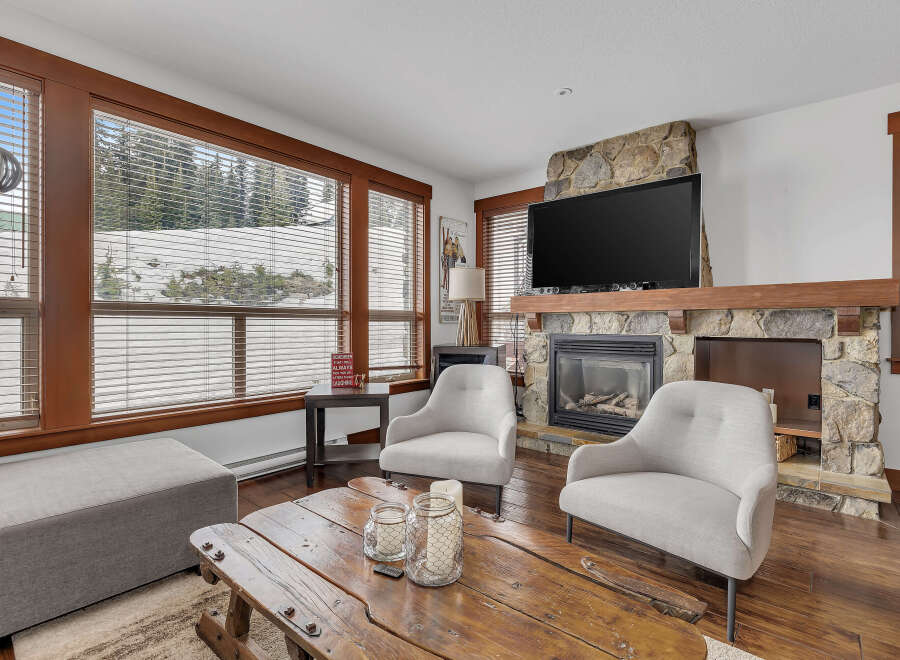 Cozy up in this stunning living room featuring a stone fireplace and a large flat-screen TV, perfect for relaxing evenings.