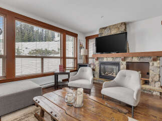 Cozy up in this stunning living room featuring a stone fireplace and a large flat-screen TV, perfect for relaxing evenings.