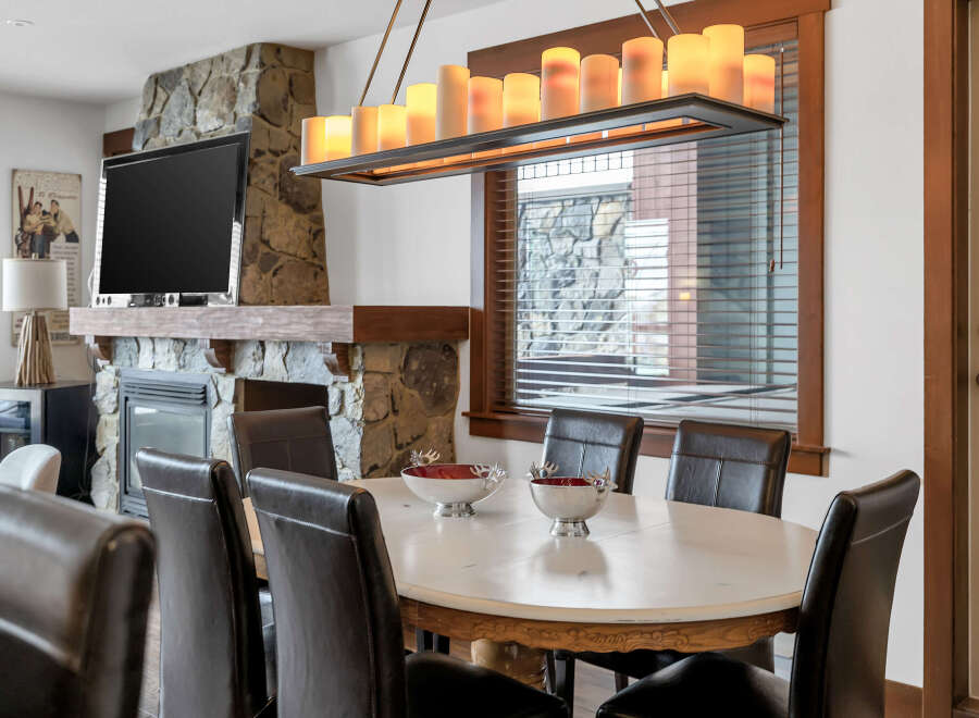 This stunning dining room features a beautiful stone fireplace and a large flat-screen TV, perfect for cozy evenings.