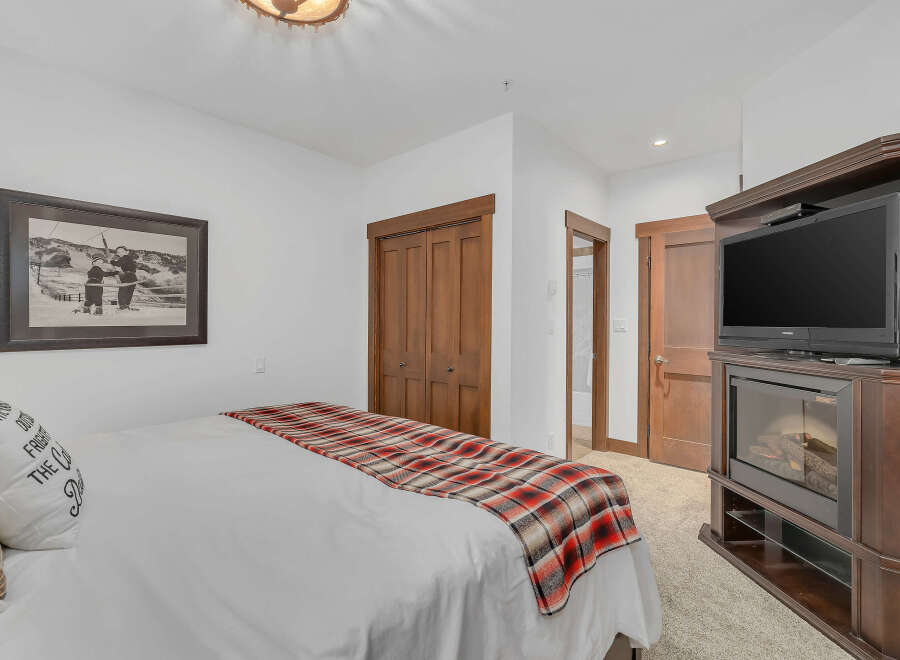 This cozy bedroom features a comfortable bed with a stylish plaid throw and a decorative pillow.