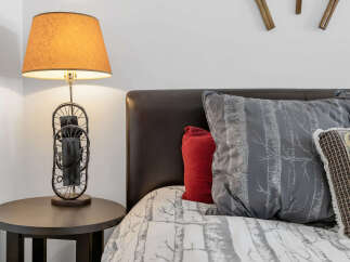 This cozy bedroom features a stylish bed with decorative pillows and a unique lamp.
