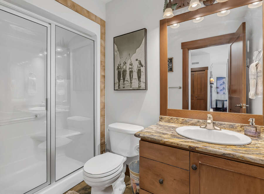 This stunning bathroom features a modern glass shower, a stylish vanity with a granite countertop, and a classic white toilet.