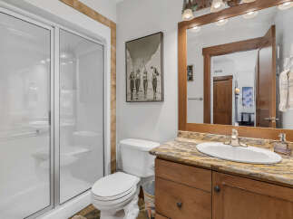 This stunning bathroom features a modern glass shower, a stylish vanity with a granite countertop, and a classic white toilet.