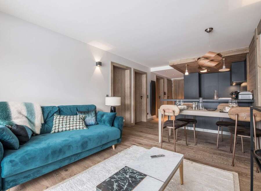 Experience luxury living in this stunning property, featuring a modern turquoise sofa and a stylish dining area.