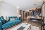 Experience luxury living in this stunning property, featuring a modern turquoise sofa and a stylish dining area.