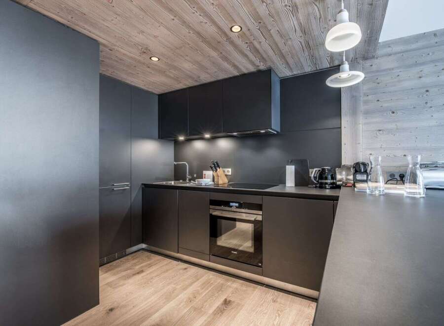 This modern kitchen boasts sleek, dark cabinetry and a minimalist design, perfect for contemporary living.