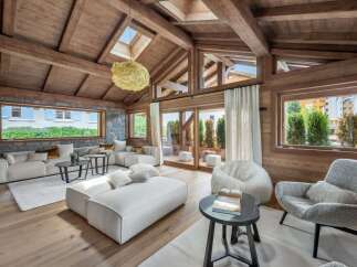 Experience luxury living in this stunning property, featuring a spacious living room with a vaulted wooden ceiling and exposed beams.