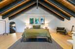 This stunning bedroom boasts a unique architectural design with exposed wooden beams and a vaulted ceiling, creating a spacious and airy feel.