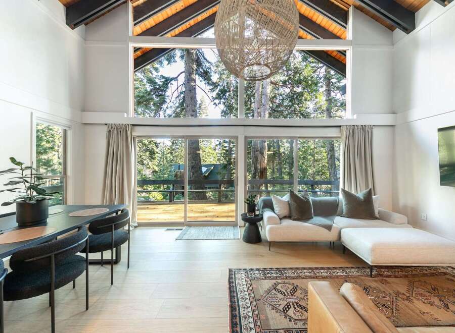 Experience the tranquility of this stunning property, featuring a spacious living area with expansive windows that frame breathtaking views of the surrounding forest.
