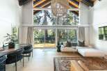 Experience the tranquility of this stunning property, featuring a spacious living area with expansive windows that frame breathtaking views of the surrounding forest.
