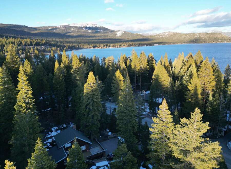 Nestled amidst towering evergreens, this stunning property offers breathtaking views of a pristine lake and snow-capped mountains.