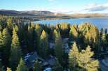 Nestled amidst towering evergreens, this stunning property offers breathtaking views of a pristine lake and snow-capped mountains.