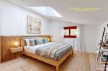 Discover the charm of this beautifully designed bedroom, featuring a cozy bed and a stylish wooden headboard.