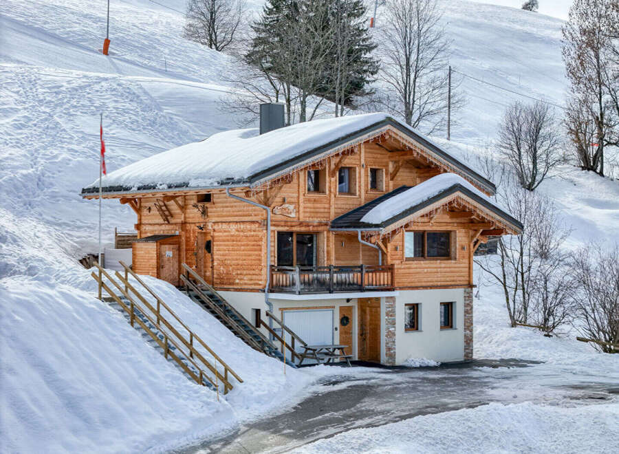 Nestled in a snowy landscape, this charming wooden chalet offers a cozy retreat.