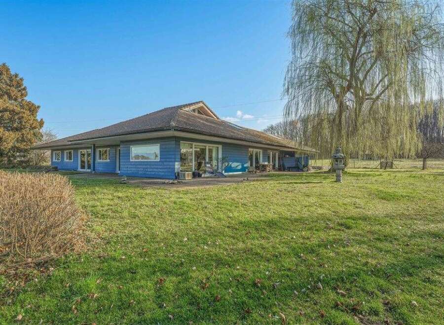 This stunning property boasts a beautiful blue exterior and a spacious, well-maintained lawn, perfect for outdoor activities.