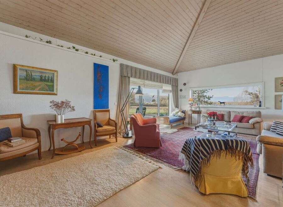 Step into this inviting living space, featuring a vaulted wooden ceiling and abundant natural light.
