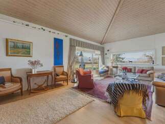 Step into this inviting living space, featuring a vaulted wooden ceiling and abundant natural light.