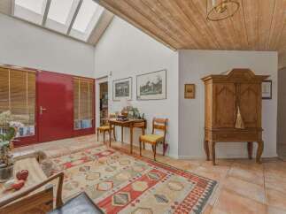 Step into this inviting entryway, featuring a striking red door and natural light pouring in from the skylights.