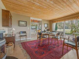 Step into this inviting dining room, featuring a beautiful wooden ceiling and a striking red rug that adds warmth and character.