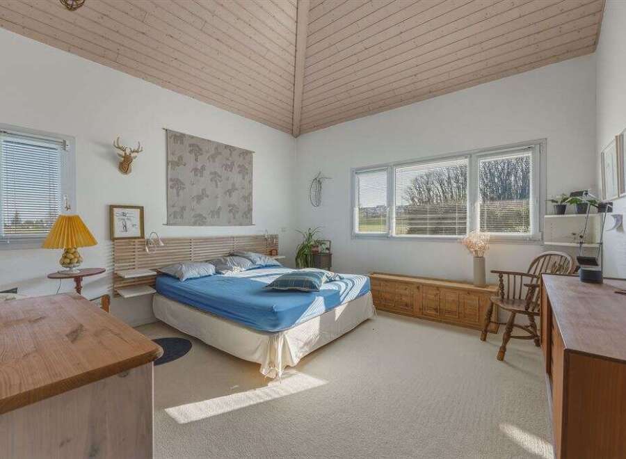 This bright and airy bedroom offers a serene retreat with its vaulted ceiling and natural light.
