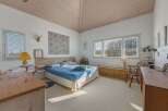 This bright and airy bedroom offers a serene retreat with its vaulted ceiling and natural light.