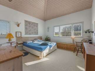 This bright and airy bedroom offers a serene retreat with its vaulted ceiling and natural light.
