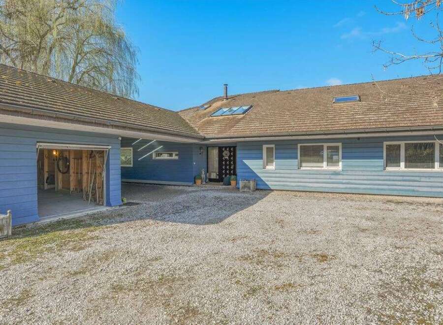 This stunning property boasts a charming blue exterior and a spacious gravel driveway, perfect for multiple vehicles.
