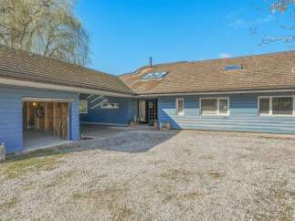 This stunning property boasts a charming blue exterior and a spacious gravel driveway, perfect for multiple vehicles.