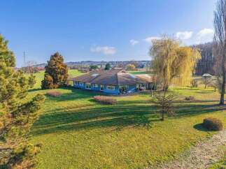 Discover this stunning property featuring a spacious, blue-sided house with a unique roof design, perfect for those seeking a blend of modern and natural aesthetics.